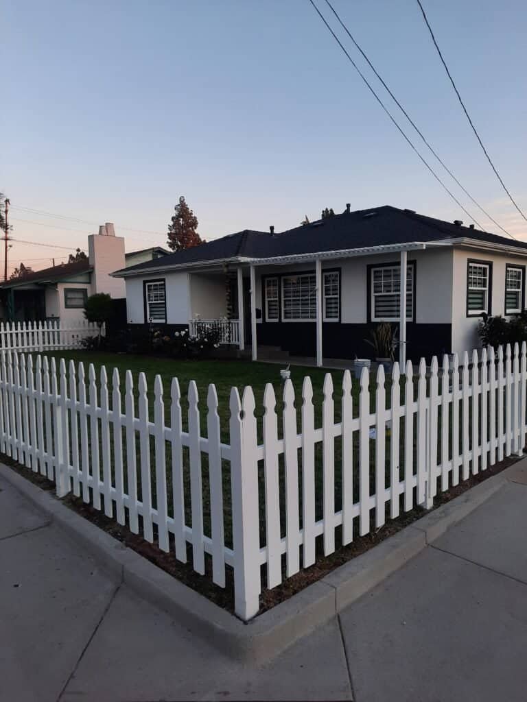 Bright White Residential House with Black Trim and White Picket Fence at Dawn.