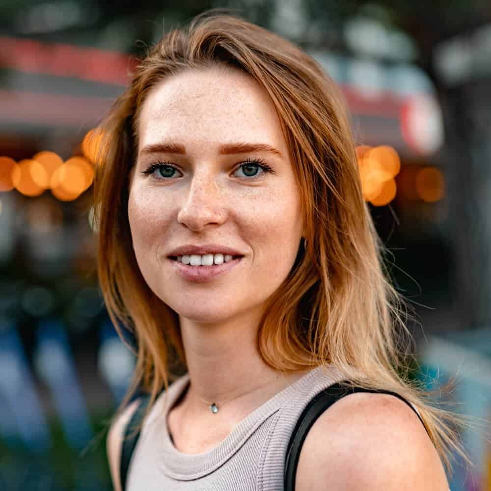 Vibrant red-haired woman smiling outdoors in urban setting showcasing professional landscaping and painting services by AAF Painting Inc. for residential and commercial properties.