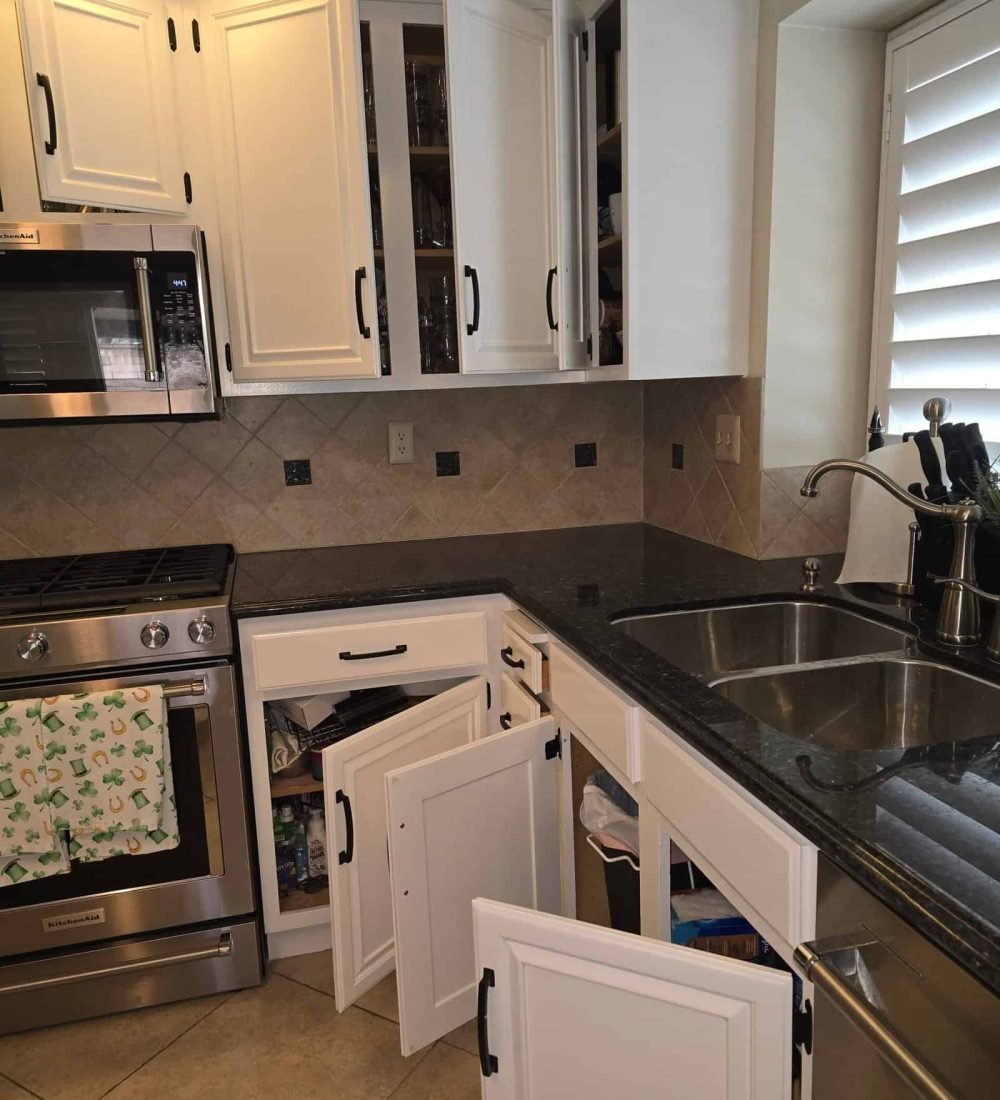 White kitchen cabinets with black handles and granite countertops, double sink, stainless steel oven and microwave, tile backsplash, kitchen organization, home renovation, AAF PAINTING INC.